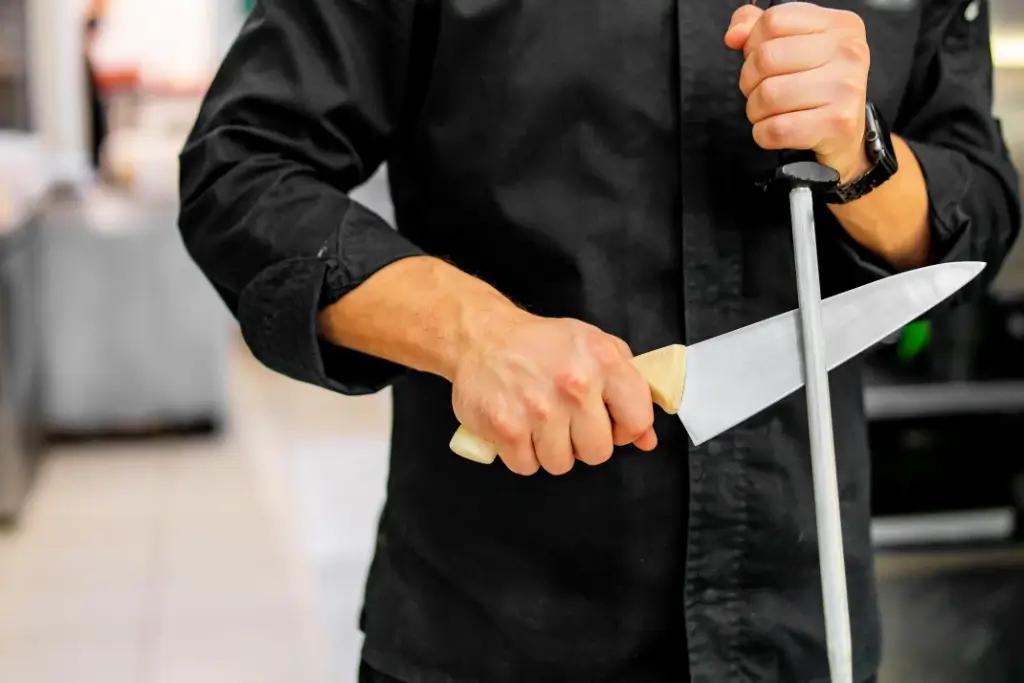 A person doing a professional knife sharpening with a honing rod.