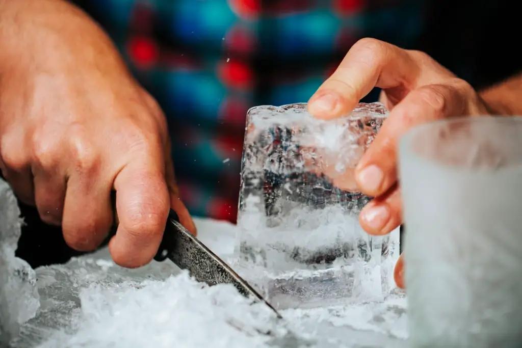 Someone using an ice knife to cut up ice.
