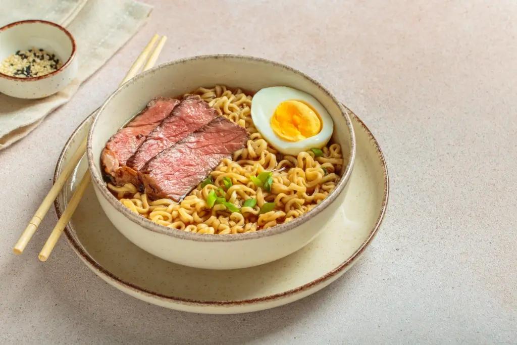 A bowl of instant ramen with beef and egg on top.